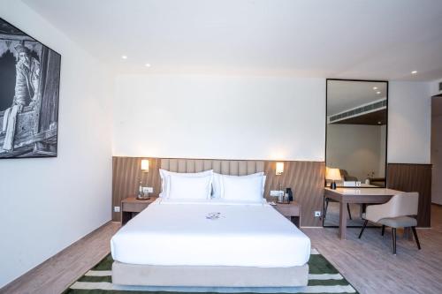 a bedroom with a large white bed and a desk at Velmore Kasauli Operated by Royal Orchid Hotel Ltd. in Kasauli
