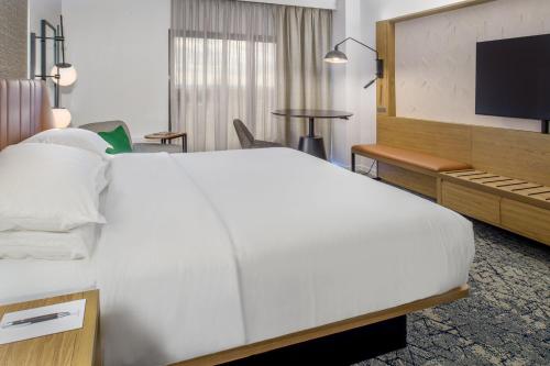 a hotel room with a large bed and a desk at Sheraton Westport Plaza in Maryland Heights