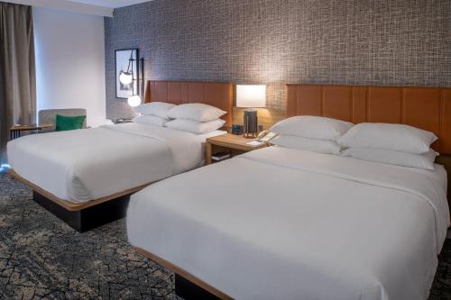 two beds in a hotel room with white sheets at Sheraton Westport Plaza in Maryland Heights
