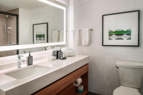 a bathroom with a sink and a mirror and a toilet at Sheraton Westport Plaza in Maryland Heights