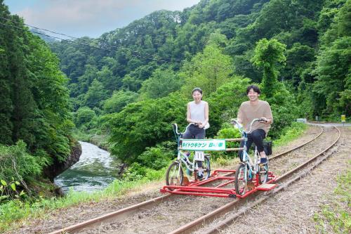 two people sitting on a train track with their bikes at KAMENOI HOTEL Akita Yuze in Kazuno