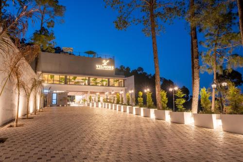 a building on a street at night with palm trees at Velmore Kasauli Operated by Royal Orchid Hotel Ltd. in Kasauli