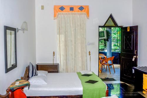 a bedroom with a bed and a window and a table at Terrel Residencies Gal Oya in Ampara