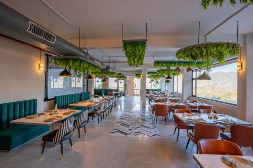 a restaurant with tables and chairs and plants at Velmore Kasauli Operated by Royal Orchid Hotel Ltd. in Kasauli