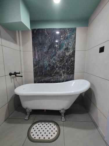 a bath tub in a bathroom with a painting on the wall at Meraki Homestay in Shillong
