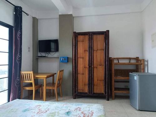 a room with a bed and a table and a table and chairs at Stanley House Seaview Apartments in Panglao