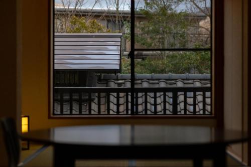 a table and a window with a view of a balcony at Ryokan Fukinoya in Yufuin