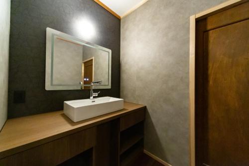 a bathroom with a white sink and a mirror at Ryokan Fukinoya in Yufuin