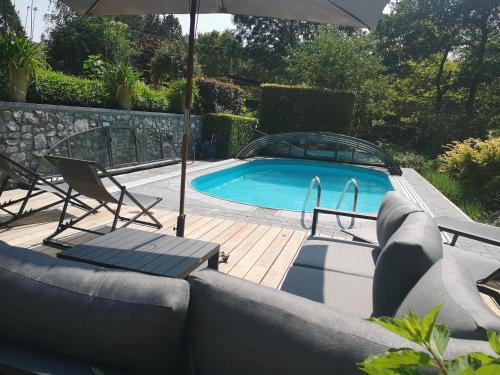 uma piscina com um sofá e cadeiras e um guarda-sol em Ardenne BnB em Marche-en-Famenne