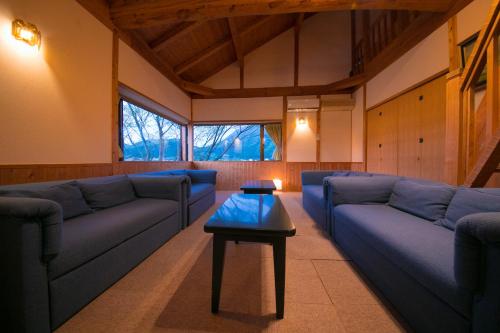 a living room with blue couches and a table at Ryokan Fukinoya in Yufuin