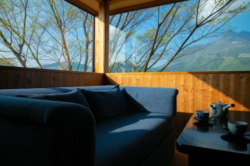 a blue couch in a room with a large window at Ryokan Fukinoya in Yufuin