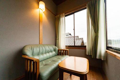 a room with a couch and a table and a window at Ryokan Fukinoya in Yufuin
