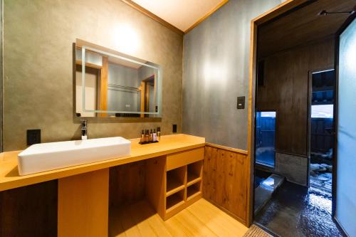 a bathroom with a sink and a mirror at Ryokan Fukinoya in Yufuin