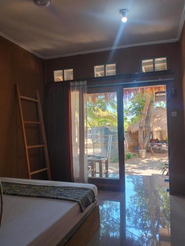 a room with a bed and a sliding glass door at Fullmoon homestay in Kuta Lombok
