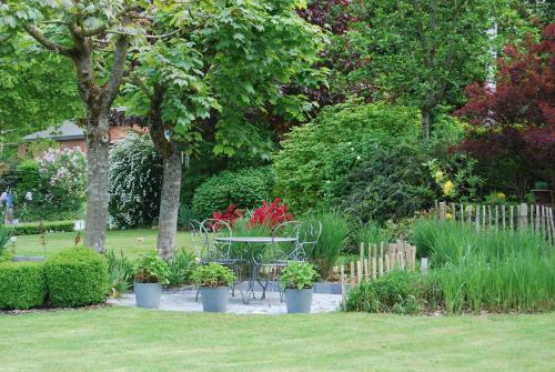 a table and chairs in a garden with plants at Ardenne BnB suite 1 à 4 personnes in Marche-en-Famenne