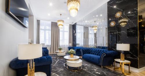 a lobby with blue couches and tables and chandeliers at Hotel Pavco in Gorzów Wielkopolski