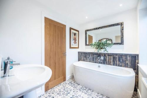 a bathroom with a tub and a sink and a mirror at Old Printing Press, Leiston in Leiston