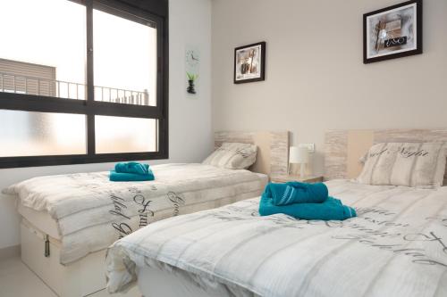 two beds in a bedroom with blue pillows on them at Playa Elisa Bay app 411 in Pilar de la Horadada