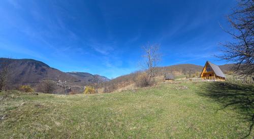 a house on a hill with mountains in the background at Etno Villas Tara&Petra in Žabljak