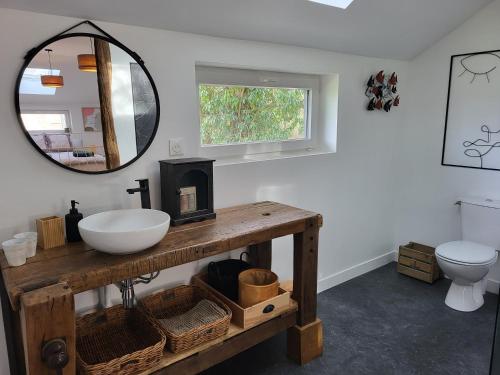 ein Bad mit einem Waschbecken und einem Spiegel in der Unterkunft Le Hangar in Coutures