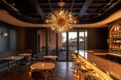 a restaurant with tables and chairs and a chandelier at Trilith Guesthouse, Fayetteville, GA, a Tribute Portfolio Hotel in Fayetteville