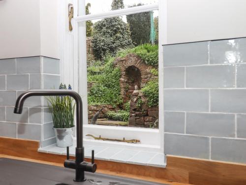 a kitchen sink with a window looking out at a garden at Rose Cottage in Teignmouth