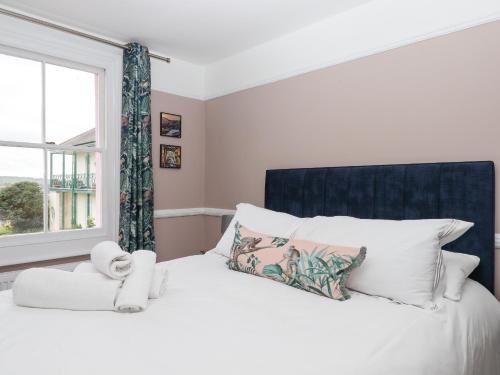 a bedroom with a white bed with a window at Rose Cottage in Teignmouth