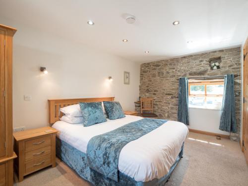 a bedroom with a large bed and a stone wall at Eirlys Llanrhystud in Llanrhystyd