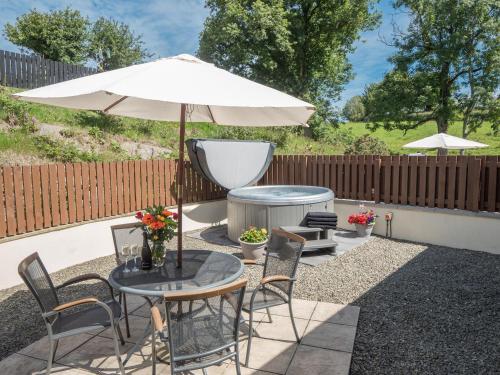 a patio with a table with an umbrella and chairs at Eirlys Aberystwyth in Llanrhystyd