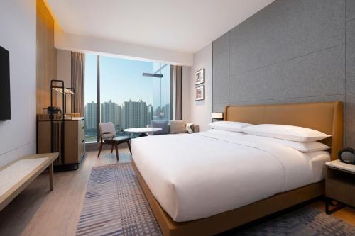 a large white bed in a room with a large window at Sheraton Taiyuan in Taiyuan