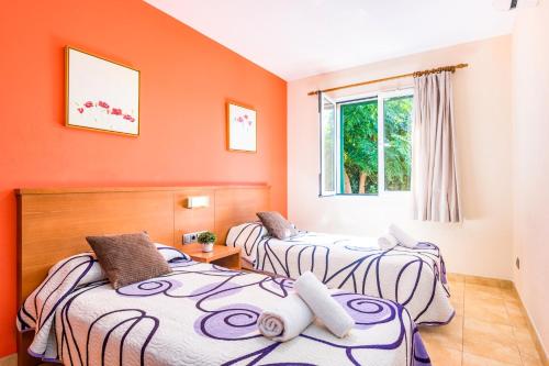 two beds in a room with orange walls at Villa Mediterraneum by Villa Plus in Cala en Forcat