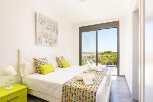 a white bedroom with a large bed and a balcony at Villa Dolce Vita by Villa Plus in Alaior