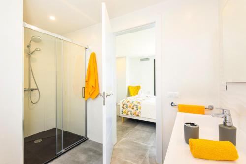 a white bathroom with a shower and a bedroom at Villa Dolce Vita by Villa Plus in Alaior