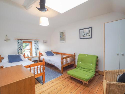 a bedroom with two beds and a green chair at Y Bwthyn Newport in Newport Pembrokeshire
