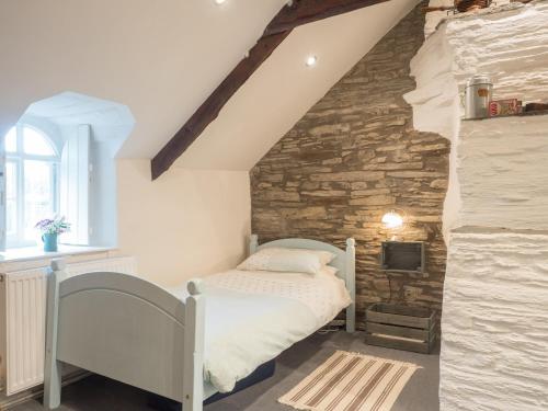 a bedroom with a bed and a stone wall at Ty Cam Abercych in Abercych