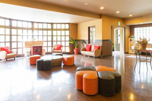 a living room with orange and gray chairs and a fireplace at Kawaguchiko Park Hotel in Fujikawaguchiko