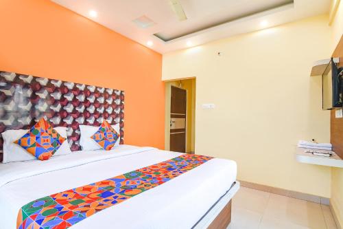 a bedroom with a large bed with colorful pillows at FabHotel Angel The Golden Key in Jojera