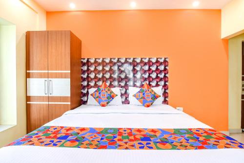 um quarto com uma cama com uma parede laranja em FabHotel Angel The Golden Key em Jojera