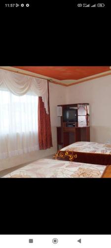 奧塔瓦洛的住宿－Juyanis Hostal，一间卧室设有一张床、一个窗口和一台电视