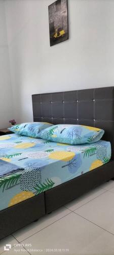 a bed with a black frame and pillows on it at Hana Homestay The Heights Residence in Ayer Keroh