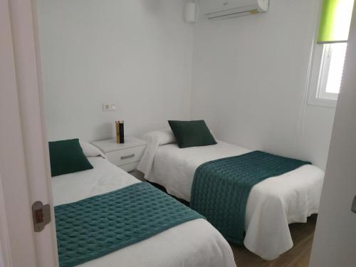 um quarto com duas camas com lençóis verdes e brancos em Casa Rural Maestros em Albanchez de Úbeda