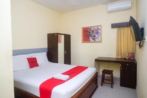 um quarto com uma cama, uma secretária e uma televisão em RedDoorz @ Swakarya Kaliurang em Yogyakarta
