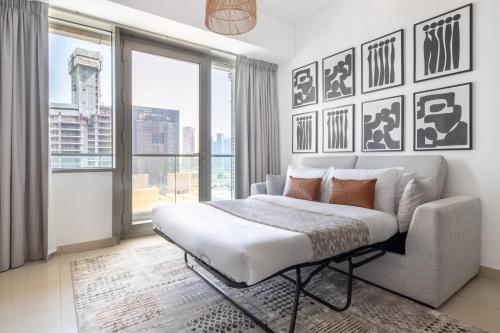 a bedroom with a bed and a couch and windows at Frank Porter - Ocean Heights in Dubai