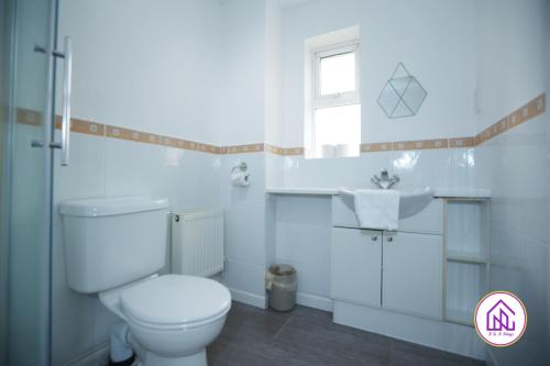 a white bathroom with a toilet and a sink at Milestone House, Large Modern House, Free Parking in Cardiff