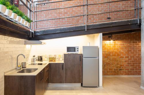 a kitchen with a white refrigerator and a brick wall at ART LOFTS Valencia by Benisur in Valencia