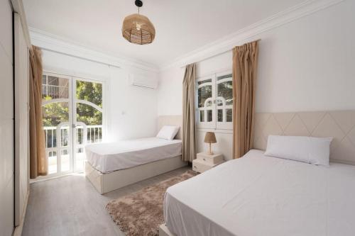 een witte slaapkamer met 2 bedden en een raam bij 2 BR unit with bohemian Style in Caïro