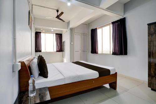ein Schlafzimmer mit einem Bett und zwei Fenstern in der Unterkunft OYO Hotel Sama Residency in Vadodara
