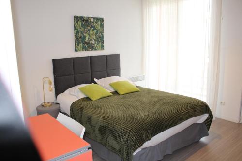 1 dormitorio con 1 cama grande y 2 almohadas verdes en City Lodge Appart Hôtel Niort en Niort