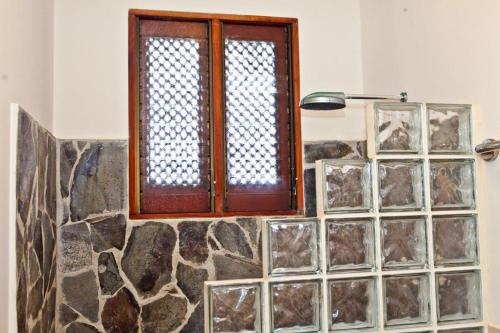 a bathroom with a window and a stone wall at Bahia Azul 3A in Jacó