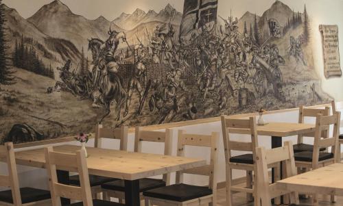 a mural in a restaurant with wooden tables and chairs at Hotel Helvetia in Müstair